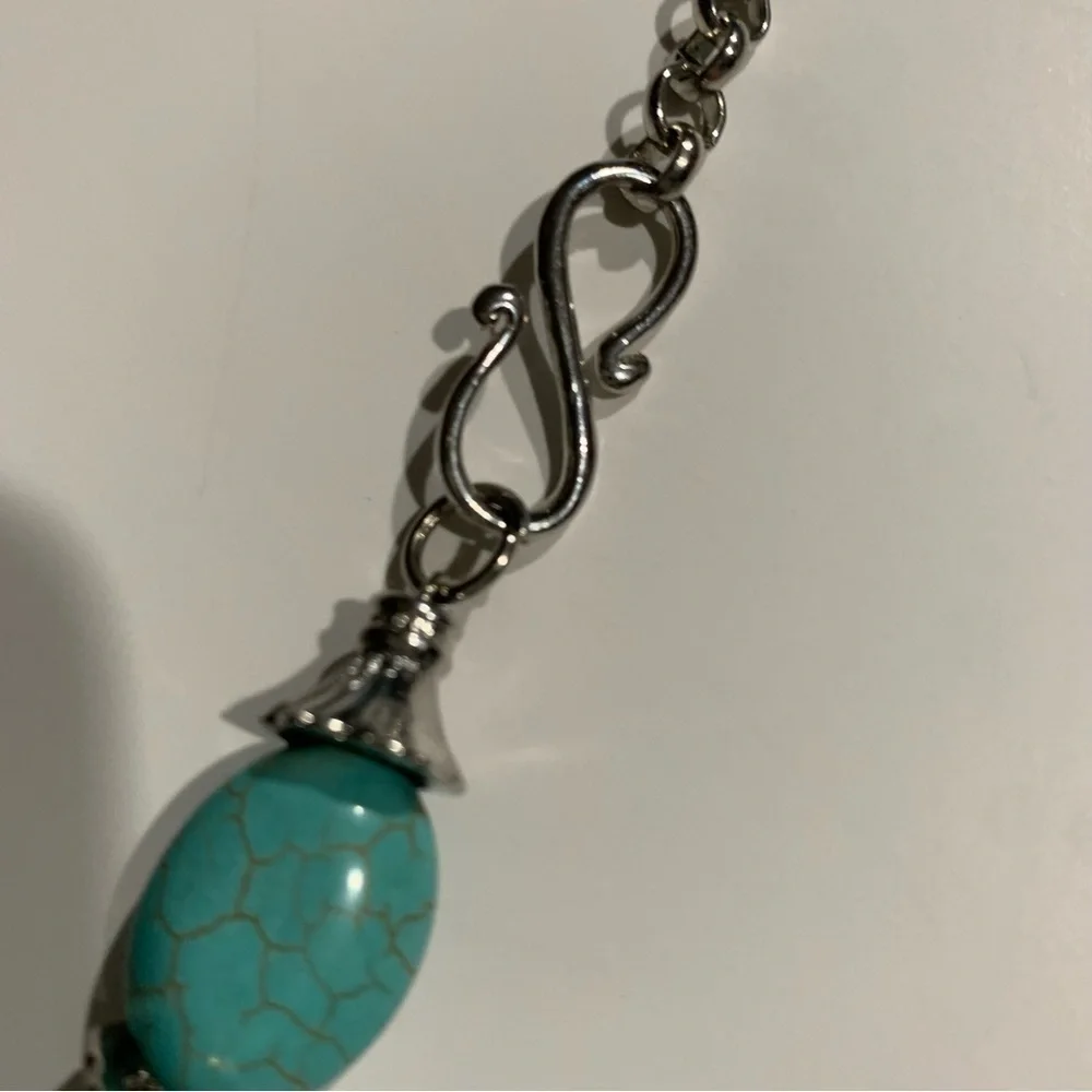 Silver tone and turquoise necklace with oversized pendant and charms.
